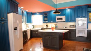 Una cocina moderna con armarios azules, un refrigerador blanco, un microondas y una estufa.