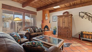 A cozy living room with a fireplace, wooden furniture, and a tiled floor. - Fort Marcy 17 | Walk to Plaza | Fireplace | Kitchen | Hot Tub | Pool | End Unit | Single Level (Santa Fe)