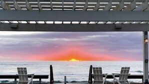 Une terrasse couverte offrant une vue sur l’océan au coucher du soleil.