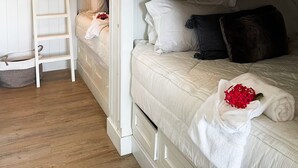 Une chambre avec un lit superposé, une échelle, un petit panier et une serviette ornée de fleurs rouges.