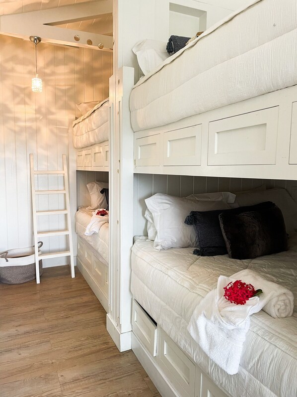 Een slaapkamer met stapelbed, een ladder, een klein mandje en een handdoek met rode bloemen.