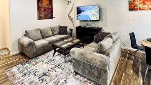 Een woonkamer met een modulaire bank, een salontafel, een flatscreen televisie en een plafondventilator.