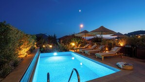 A swimming pool with lounge chairs and umbrellas, surrounded by vegetation and a night sky. - Villa Sole Sidyma – Luxury Villa with Heated Pool, Central Location, Bay Views (Antalya)