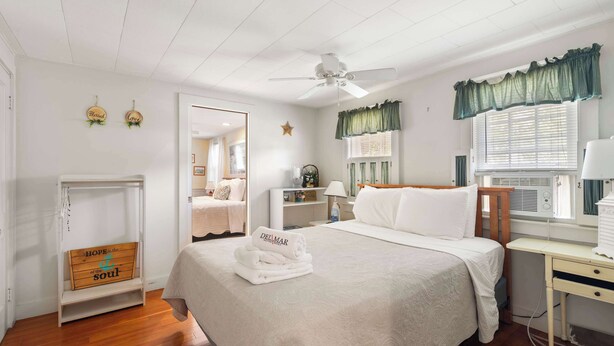 Habitación de hotel con cama, mesita de noche, lámpara, ventana con cortinas y escritorio con silla.