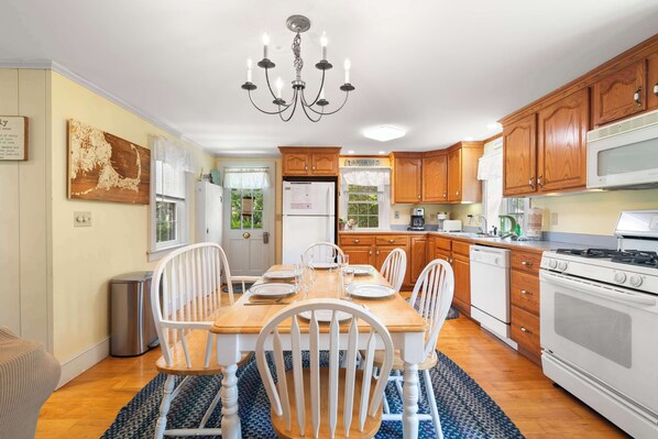 A kitchen with wooden cabinets, a white refrigerator, a stove, and a dining table set for four.