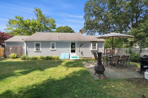 A residential house with a patio area, outdoor furniture, and a grill.