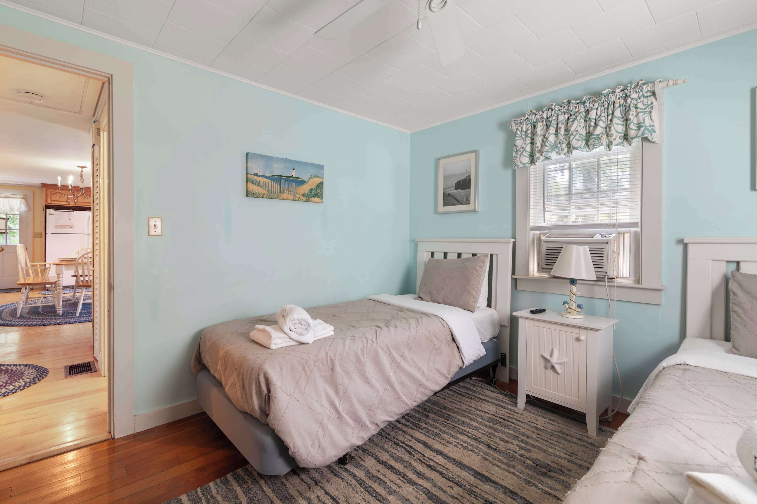 A bedroom with a bed, bedside tables, a window with curtains, and a door leading to another room.