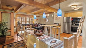 A spacious kitchen with wooden cabinets, a stainless steel refrigerator, and a large island with a bowl of pinecones.