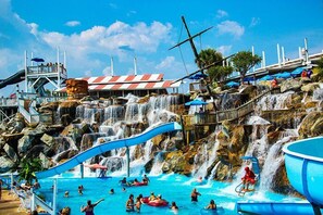 Ein Wasserpark mit einem großen Pool, zahlreichen Wasserrutschen und einem Wasserfall.