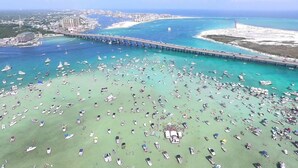 An aerial view of a beach with numerous boats and a pier extending into the water. - 2BR Updated Condo | 2 Pools, Steps to Beach (Miramar Beach)