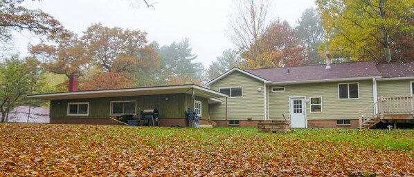 A two-story house with a covered porch and a front yard covered in fallen leaves.