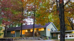 A two-story house with a front porch, a staircase leading to the second floor, and a garage. - 2500 SF Remodeled Cottage on a Quiet Lake in the Woods (Rhinelander)