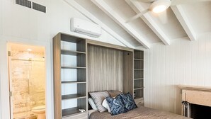 Een slaapkamer met een hoogslaper, inbouwplanken, een plafondventilator en een open haard.
