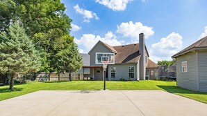 A residential property with a basketball hoop, a well-maintained lawn, and a house with a chimney.