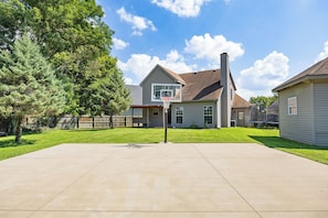 A residential property with a basketball hoop, a well-maintained lawn, and a house with a chimney.