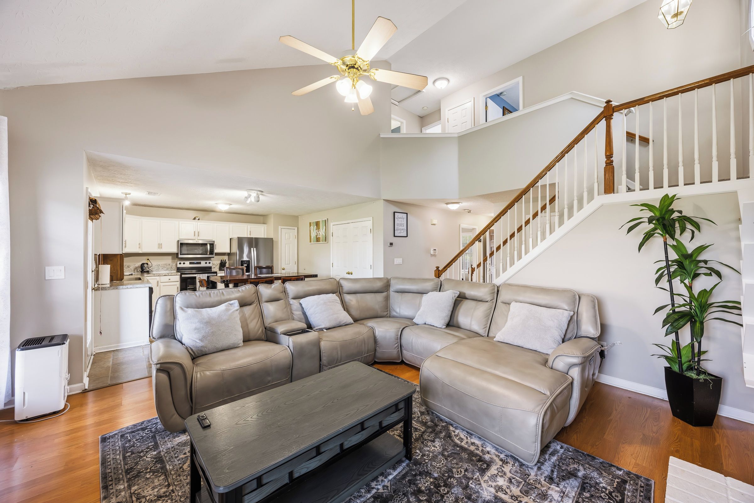 A spacious living room with a sectional sofa, a coffee table, and a ceiling fan.