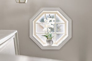 Una habitación con un amplio ventanal octogonal, una planta en maceta en el alféizar y una pared blanca.