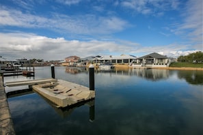 Een jachthaven met aangemeerde boten, een rustig waterlichaam en huizen op de achtergrond.