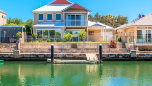 A two-story house with a balcony, a swimming pool, and a dock extending into the water.