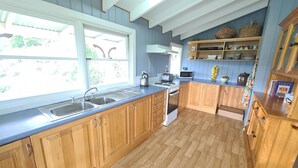 A kitchen with wooden cabinets, a stainless steel sink, a stove, and a microwave. - Foster - Nature Retreat -  Nippards Nature Cottage (Woorarra West)