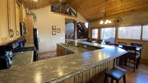 A kitchen with wooden cabinets, a granite countertop, a built-in stove, and a dining area with wooden chairs and a table.