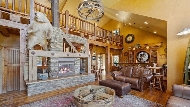 A rustic interior with a stone fireplace, a bear sculpture, a leather sofa, and a wooden coffee table.