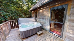 A hot tub on a wooden deck with a glass door leading to an interior space. - Tanglewood Cabin in Hocking Hills (with WiFi) (Rockbridge)