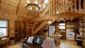 A wooden cabin interior with a living room, kitchen, and a staircase leading to an upper level. - Tanglewood Cabin in Hocking Hills (with WiFi) (Rockbridge)