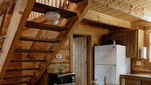 Un intérieur en bois comprenant une table à manger, des chaises, un réfrigérateur et un four à micro-ondes.