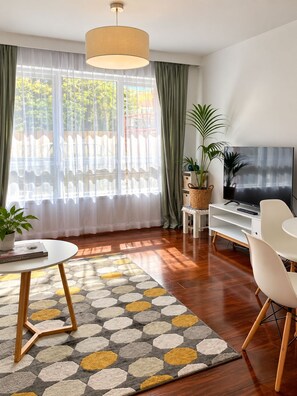 A modern living room with a television, a coffee table, and a sofa. - Poets Retreat (Elwood)