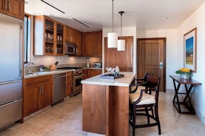 A modern kitchen with wooden cabinets, a central island, and a dining area with chairs.