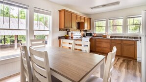 Una cocina moderna con armarios de madera, una mesa de comedor con sillas y ventanas grandes.