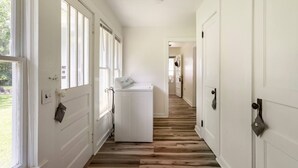 Un pasillo con puertas blancas, una lavadora y suelo de madera.