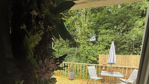 A wooden deck with a table and chairs, surrounded by a wooden fence and greenery. - “Quirky Cottage” 2 double rooms (Dumfries)