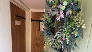 A hallway with a wooden door, a sign reading 'Guest Room,' and a wall-mounted floral decoration. - “Quirky Cottage” 2 double rooms (Dumfries)
