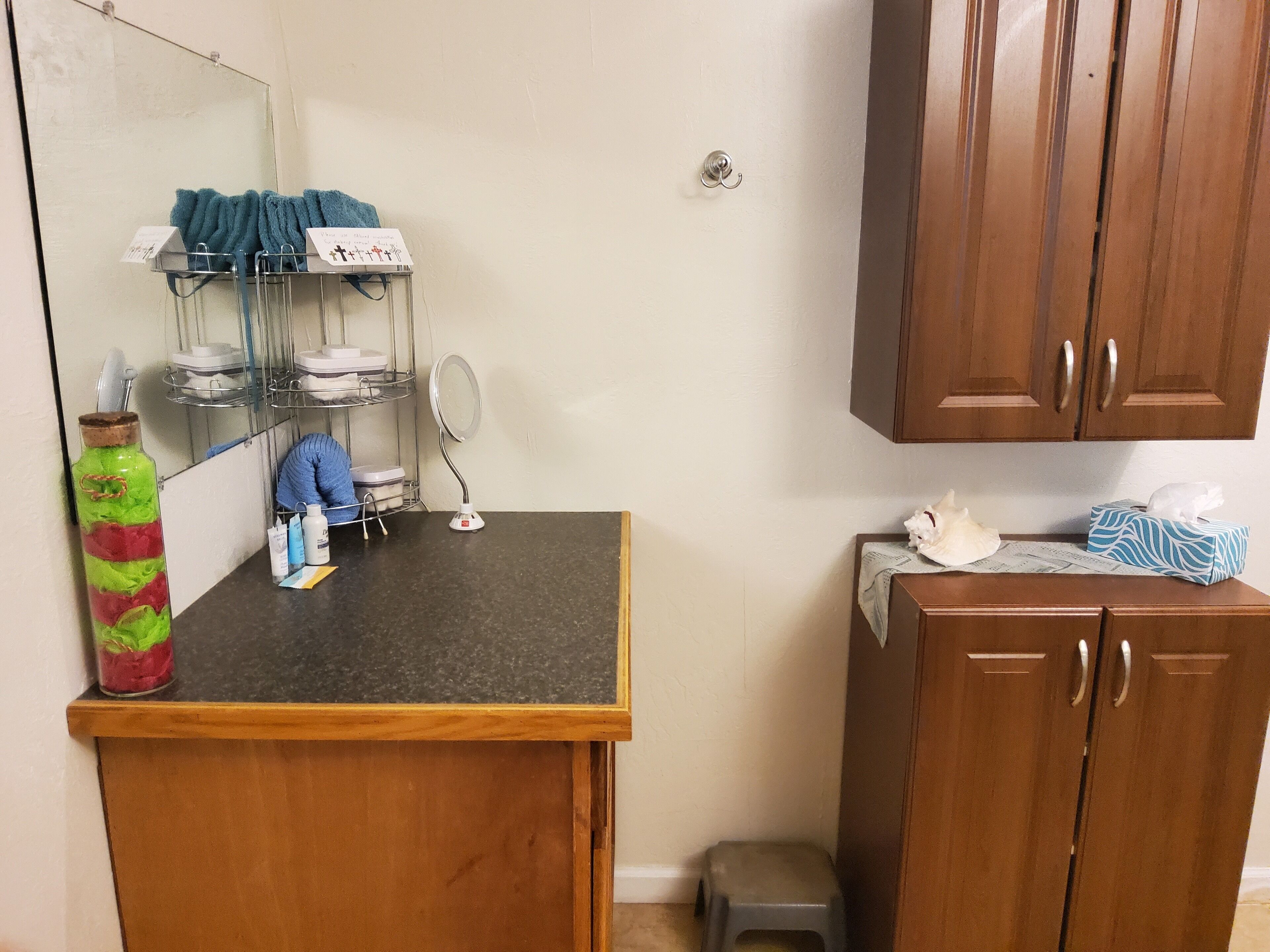 A bathroom with a wooden cabinet, a mirror, a sink, and a shelf with toiletries.