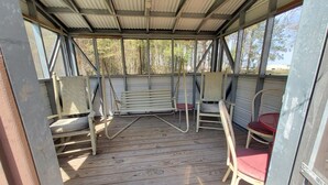 Un espace extérieur aménagé, abrité et doté d’un plancher en bois et de chaises à structure métallique.