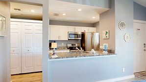 A modern kitchen with white cabinets, stainless steel appliances, and granite countertops.