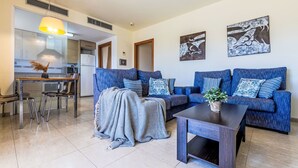 A modern living room with a sofa set, a coffee table, and a dining area with chairs. - Golden Beach by Interhome (St Carles de la Ràpita)