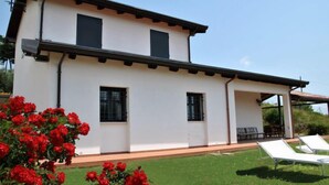 Una casa a due piani con tetto piatto e patio coperto.