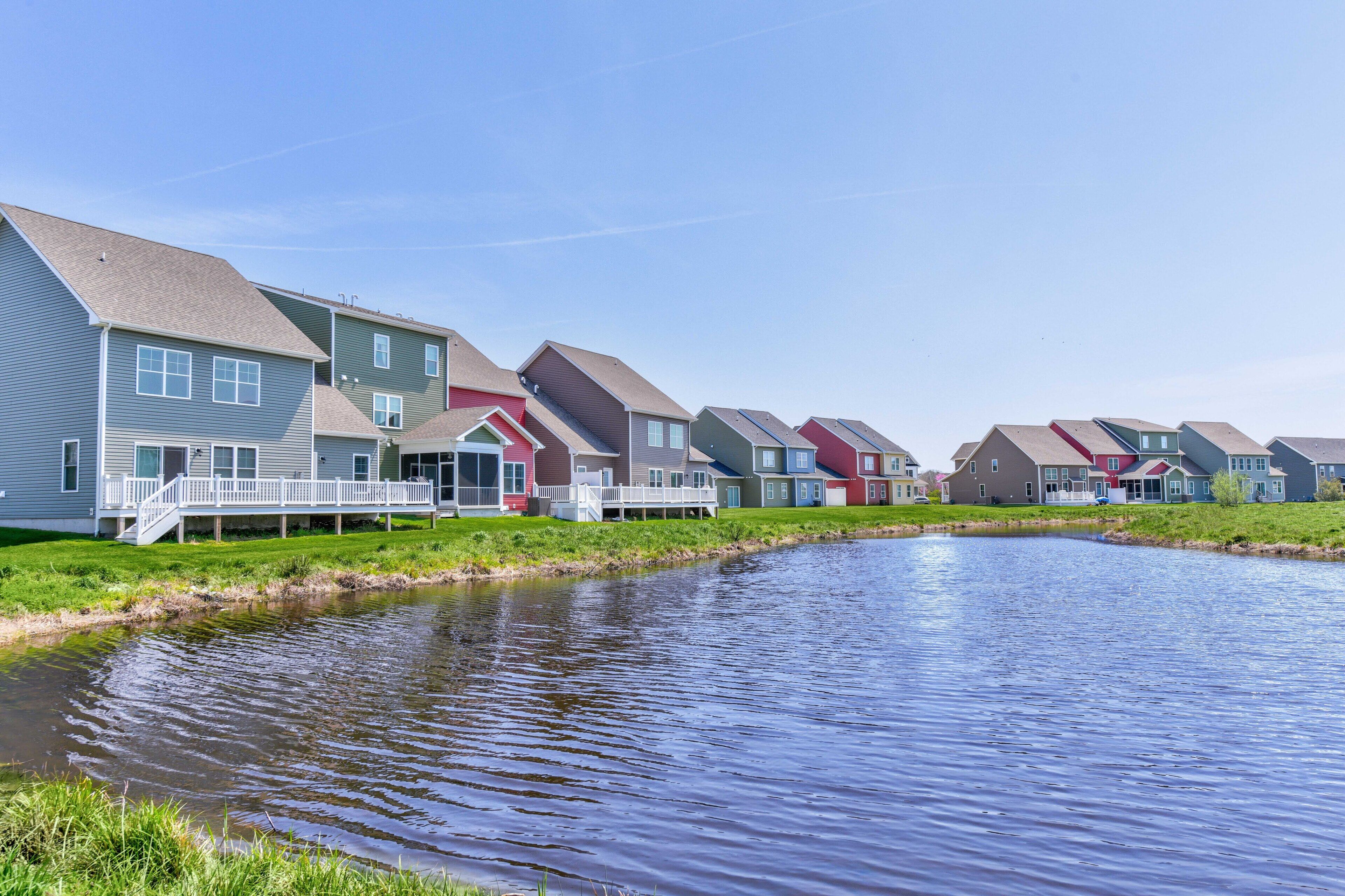 A row of modern houses with a small pond in the foreground.