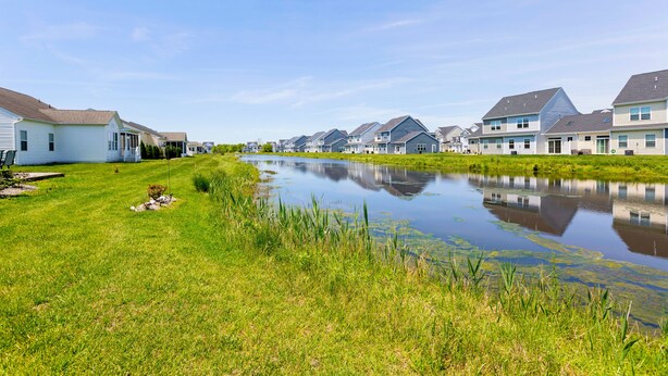 Een rij eenlaags huizen met een klein vijvertje op de voorgrond.