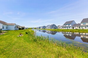 A row of single-story houses with a small pond in the foreground.
