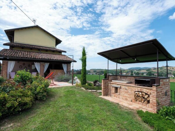 Una casa con patio, una parrilla y vistas al campo.