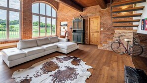 A spacious living room with a large white sectional sofa, a rustic cowhide rug, and a view of a green landscape through large windows. - La Bell'aria by Interhome (Frinco)