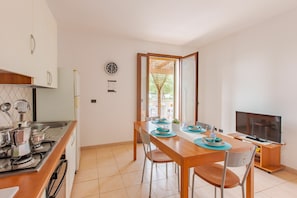 A modern kitchen with a dining area, a TV, and a view of the outdoors.