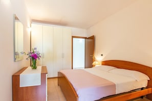A hotel room with a bed, a nightstand, a mirror, a wardrobe, and a door.