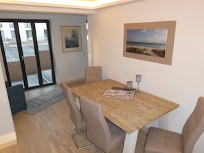A dining area with a wooden table, four chairs, two wine glasses, and a board game. - Apartment 'Gardensuite Binz' with Pool, Wi-Fi & Terrace (Binz)