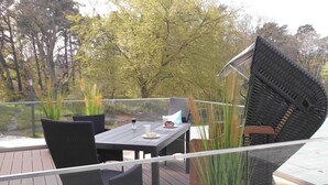 A deck with a table and chairs, surrounded by potted plants and a view of trees. - Apartment 'Gardensuite Binz' with Pool, Wi-Fi & Terrace (Binz)