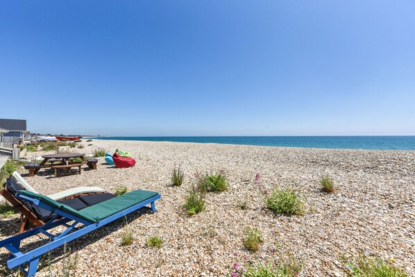 A pebble beach with lounge chairs and a picnic table. - Seasidings, Pagham - sleeps 10 guests in 5 bedrooms (Bognor Regis)
